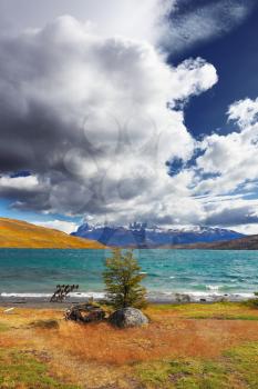 The gale on Lake Laguna Azul. A huge cloud covers the sky. In the distance the mountains with snow-capped