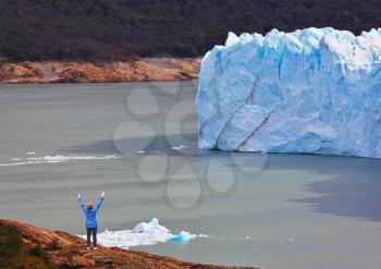 Giant lake Perito Moreno glacier. The woman - tourist admire the white-blue icy splendor