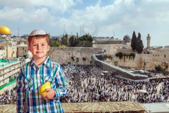 Autumn Jewish holiday Sukkot.  The greatest shrine of Judaism is the Western Wall of the Temple. Handsome little boy in skullcap with etrog