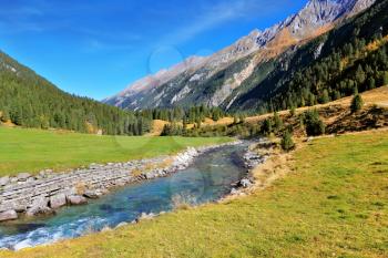 Headwaters of waterfalls - the narrow fast  river among green mountain meadows. National Park Krimml Waterfalls in Austria