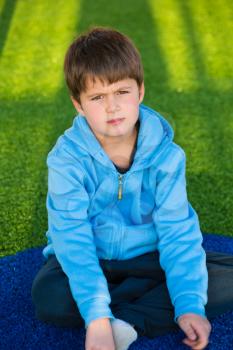 Playground in winter sunny day. Beautiful six year old boy posing on artificial turf