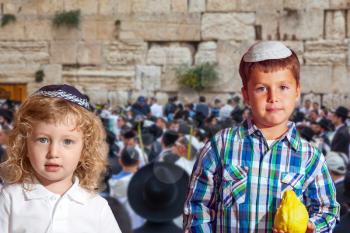 Autumn Jewish holiday Sukkot. The Western Wall of the Temple. Two beautiful Jewish boys in skull-caps with etrog