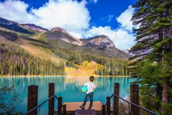 Emerald Lake in Yoho National Park in the Canadian Rockies. The seven-year slender boy with the globe in hands admire nature.