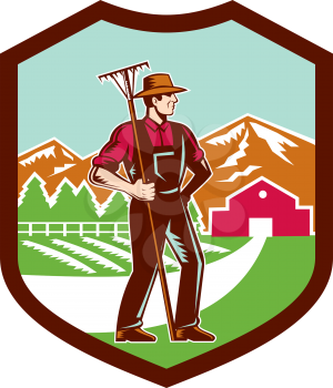 Illustration of organic farmer with rake facing side set inside shield crest with mountain trees house farm barn in the background done in retro woodcut style.
