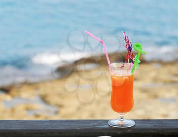 one orange cocktail against sea and coastline