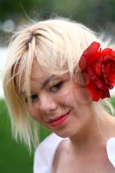 A stunningly beautiful young blond woman with red flower in hair