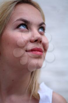 A stunningly beautiful young blond woman with bright blue eyes against wall