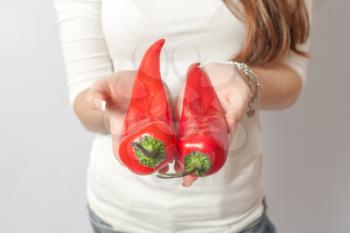 Woman in white shirt holding fresh red chili peppers in her hands
