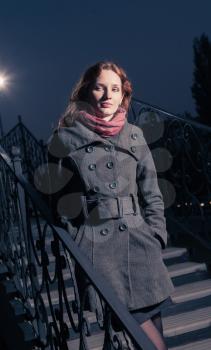 redhead 20s women on the stairs outdoor in autumn park, weared scarf and coat