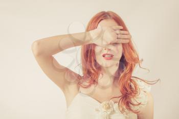 Toned image. Young redhead woman, girl covering her eyes on white background. Covered her eyes with her hands