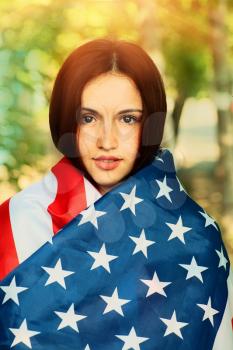 Serious young woman warp in US american flag