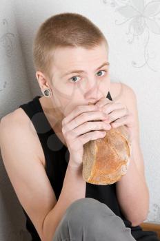 hungry teenager sitting in the corner and eat bread