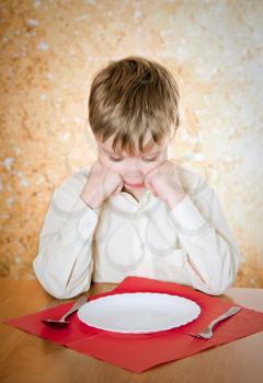 pensive child looks at the empty plate