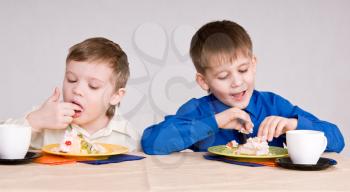 two boys eating a cake his hands