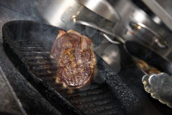 Royalty Free Photo of a Steak Grilling in a Cast-Iron Pan