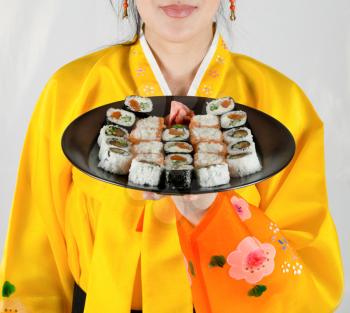 woman at bright cloth holding plate with fresh sushi set on it