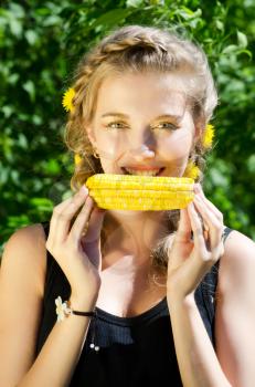Close-up outdoor portrait of young beauty woman eating corn-cob