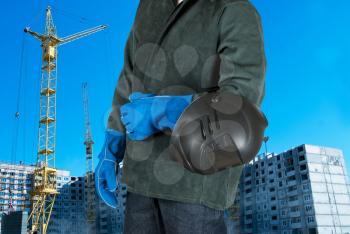 male welder closeup with welding equipment on building background