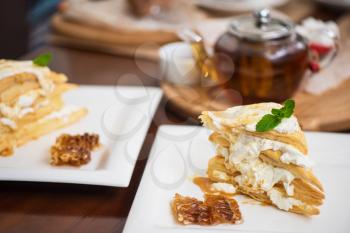 Honey cake with vanilla cream at white plate