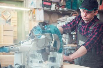 Construction worker cutting wooden board with circular saw