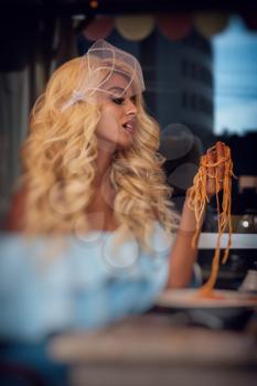 Food, people and leisure creative concept - beauty blonde young woman eating pasta in cafe