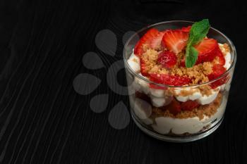 Strawberry with cookie and cream dessert decorated with mint leaf on black wooden background, with copyspace