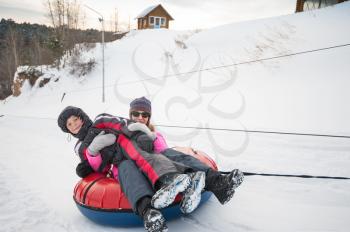 Mother and her son having fun on a snow tube, at beauty winter day