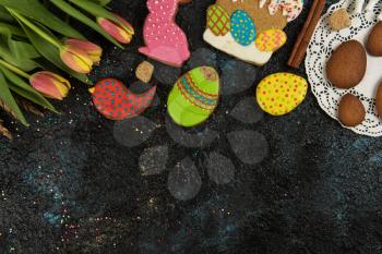 Tulips and gingerbread cookies on darken concrete background for Easter.