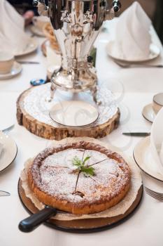 Apples pie with samovar on the served table