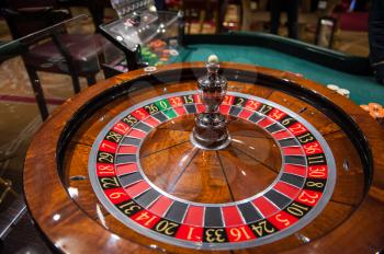 Casino, gambling and entertainment concept - roulette table and stack of poker chips