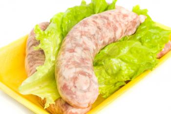 Uncooked Sausage on salad leaf over white