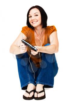 Sitting woman listening to music on an media player isolated over white