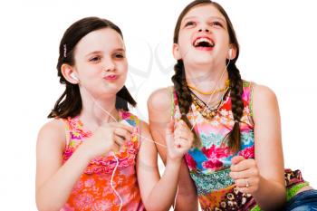 Girls listening to MP3 player and smiling isolated over white