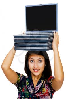 Confident woman carrying a stack of laptops isolated over white