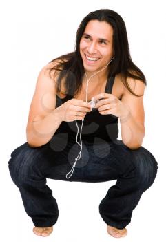 Young man listening to MP3 player and smiling isolated over white