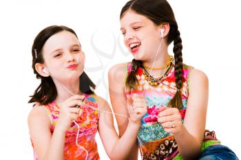 Close-up of girls listening to MP3 player and smiling isolated over white