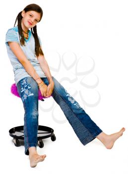Portrait of a girl sitting on a stool and smiling isolated over white