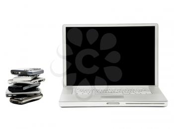 Stack of mobile phones near a laptop isolated over white