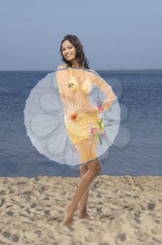Portrait of a female fashion model holding a parasol on the beach