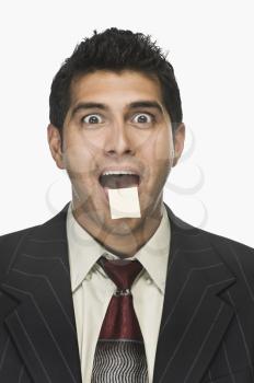 Portrait of a businessman surprised with an adhesive note on his lips