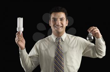 Businessman comparing a light bulb with an energy efficient lightbulb