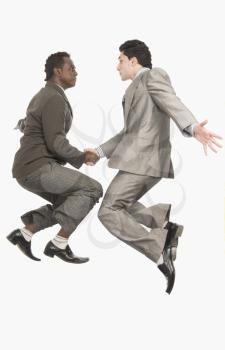 Two businessmen shaking hands in mid-air