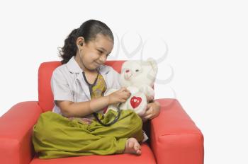 Girl examining a teddy bear with a stethoscope