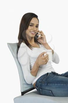 Woman talking on a mobile phone and drinking coffee