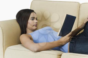 Woman resting on a couch and reading a book
