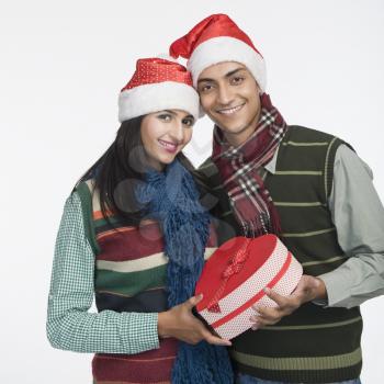 Portrait of a couple holding a Christmas present and smiling