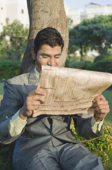 Businessman reading a newspaper in a park