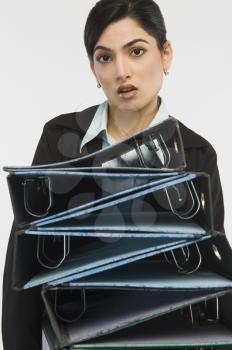 Businesswoman holding stack of binders