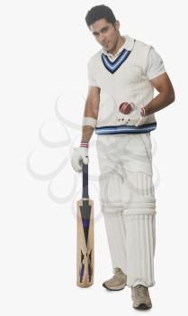 Portrait of a cricket batsman holding a bat and a ball