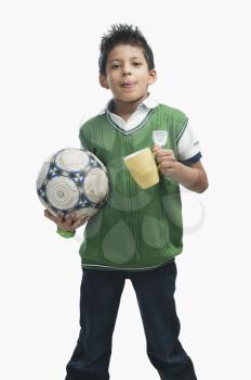 Boy holding a soccer ball and drinking hot chocolate